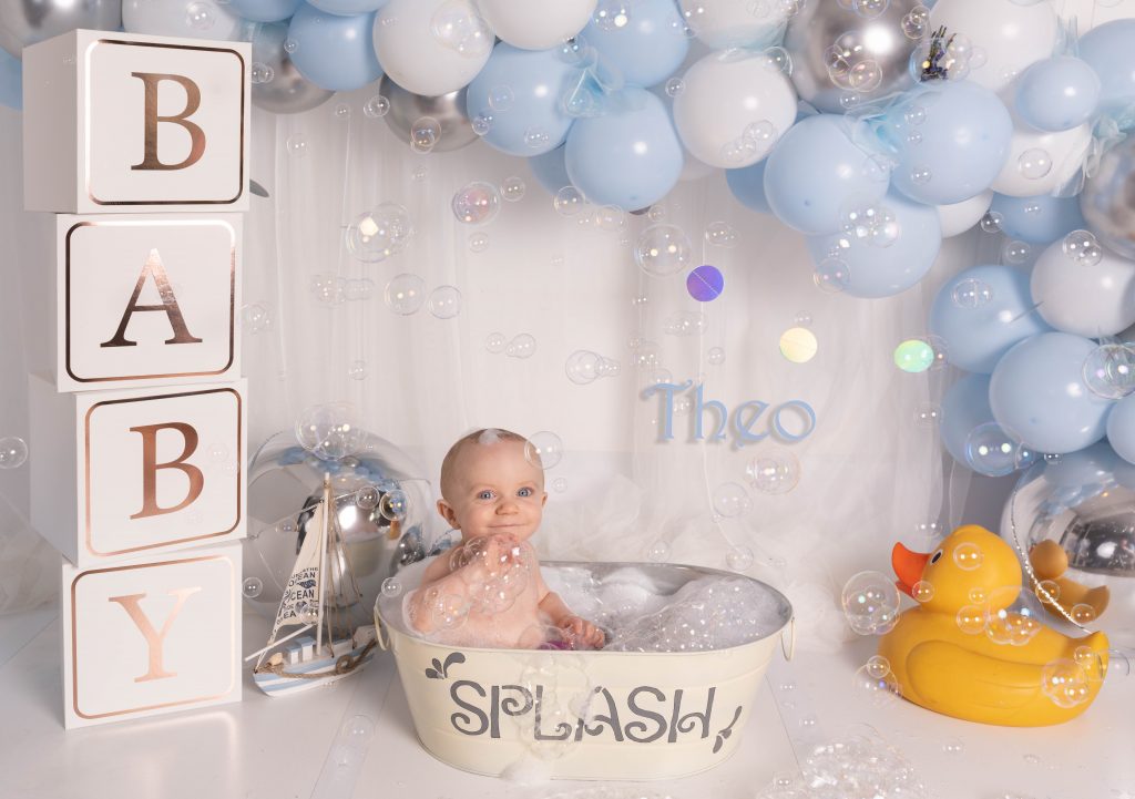 Baby in splash bath with bubbles and balloons