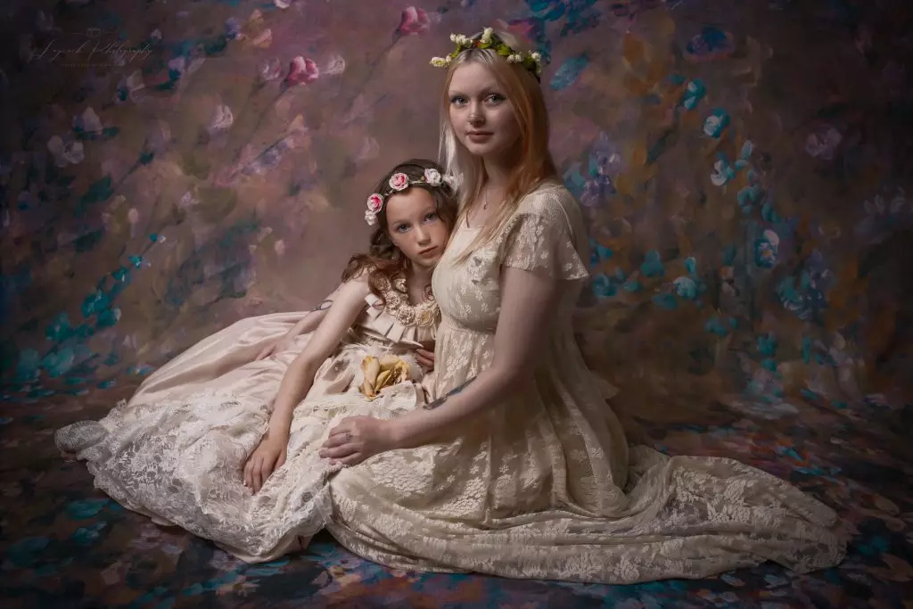 Mother and daughter fine art portrait in Stalybridge studio wearing elegant ivory lace dresses and floral crowns against a hand-painted floral backdrop.
